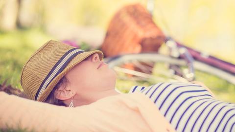 Eine erwachsenes Frau ruht sich im New Yorker Central Park aus. Im Hintergrund ist ein Fahrrad und eine Art Picknickkorb zu erkennen. Eine erwachsenes Frau ruht sich im New Yorker Central Park aus. Im Hintergrund ist ein Fahrrad und eine Art Picknickkorb zu erkennen.