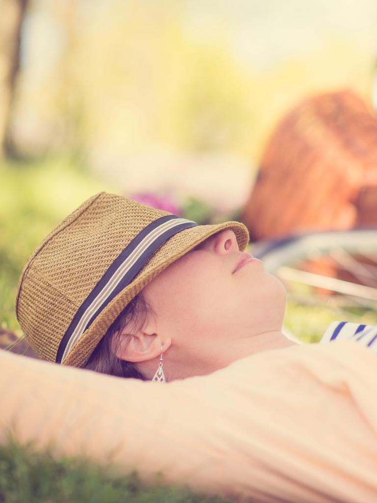 Eine erwachsenes Frau ruht sich im New Yorker Central Park aus. Im Hintergrund ist ein Fahrrad und eine Art Picknickkorb zu erkennen.
