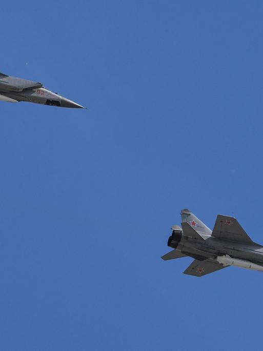 Zwei russische Kampfflugzeuge des Typs MiG-31 am blauen Himmel.