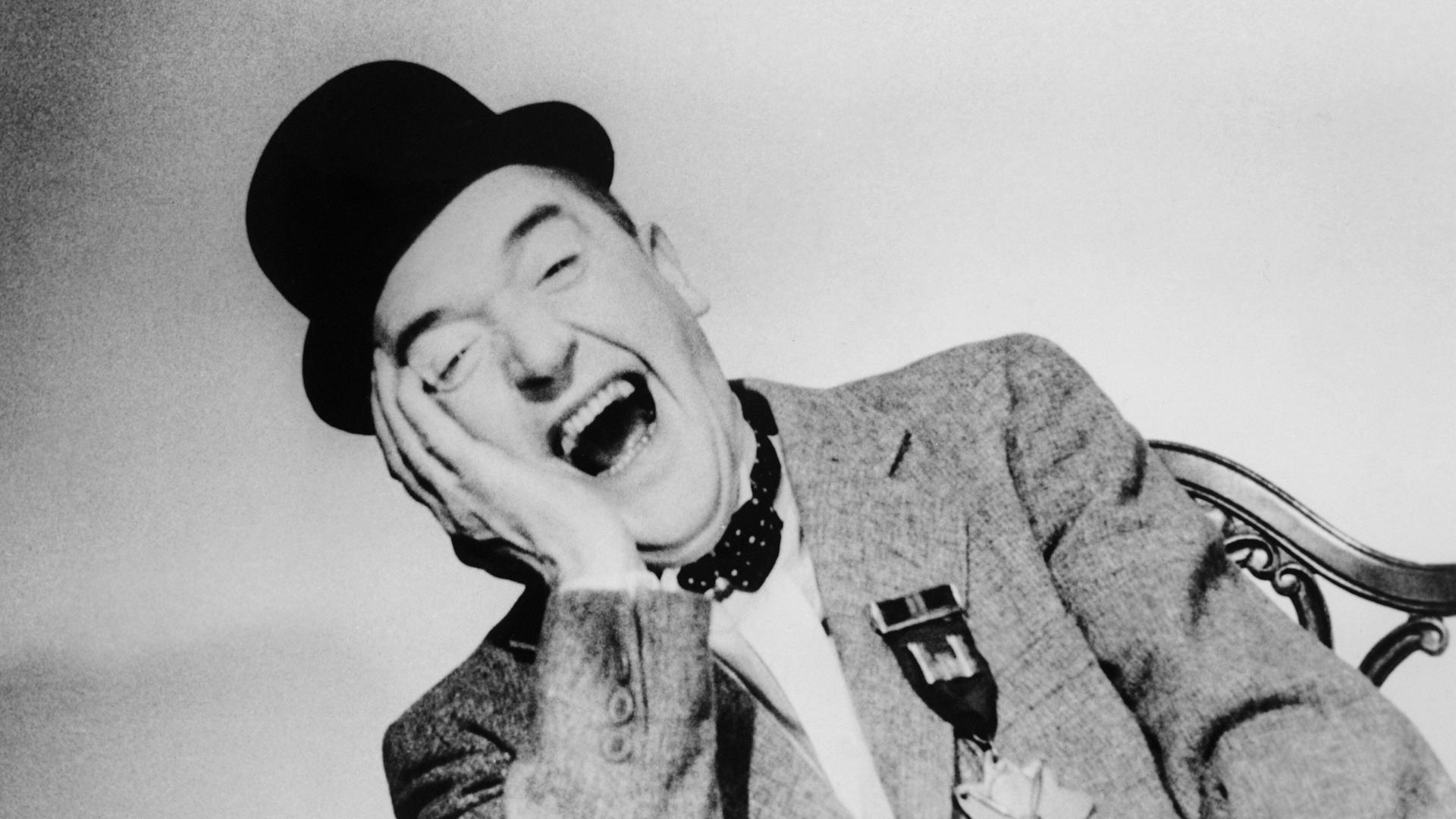 Schwarzweißporträt des Komikers Stan Laurel, der herzlich lacht