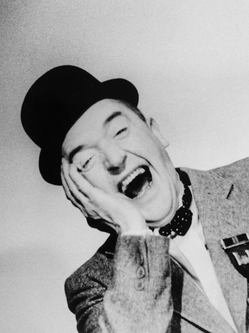 Schwarzweißporträt des Komikers Stan Laurel, der herzlich lacht