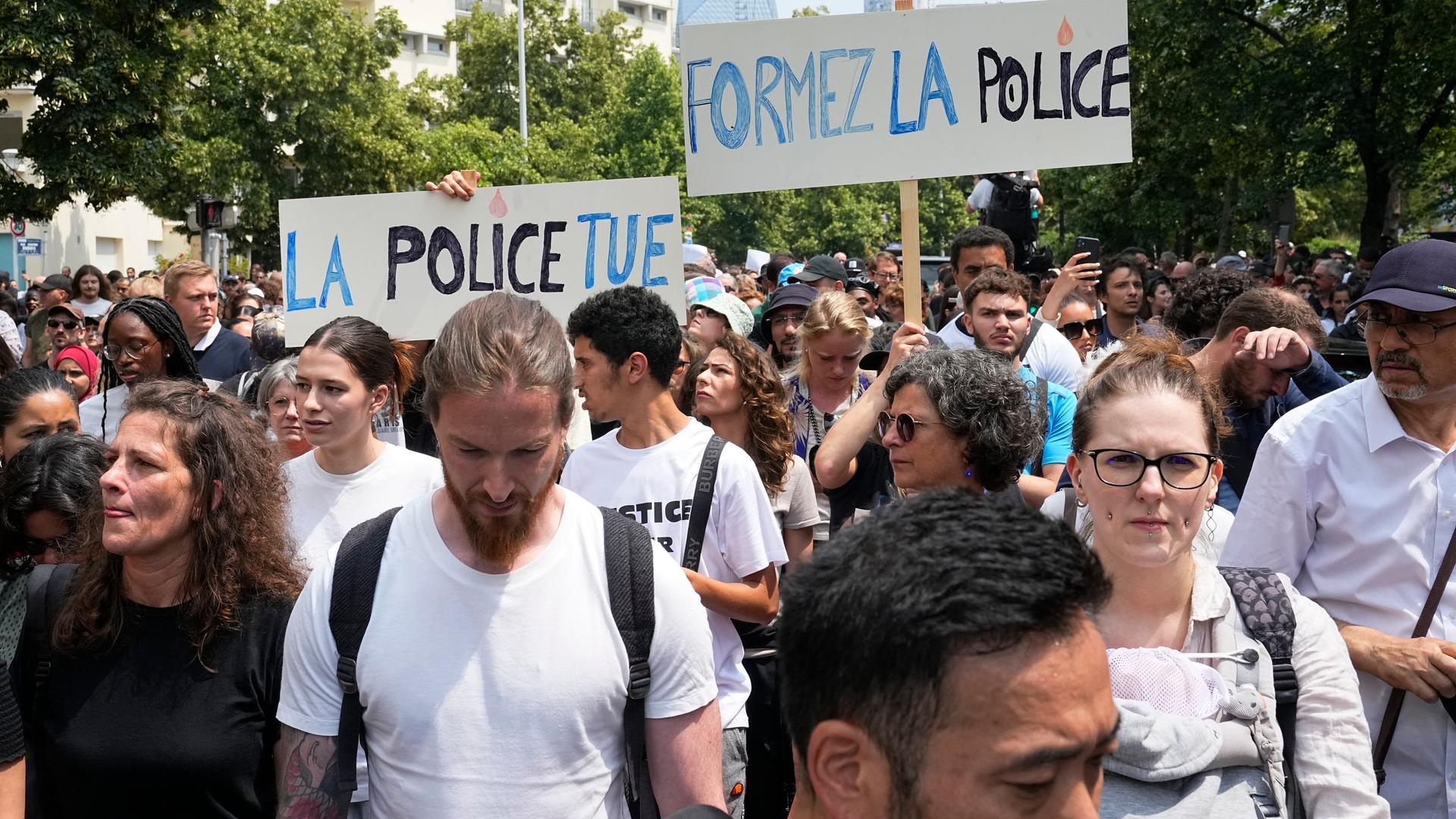 Demonstranten ziehen durch eine Straße. Einige tragen Schilder, auf denen zum Beispiel auf französisch "Die Polizei tötet" zu lesen ist. Demonstranten ziehen durch eine Straße. Einige tragen Schilder, auf denen zum Beispiel auf französisch "Die Polizei tötet" zu lesen ist.