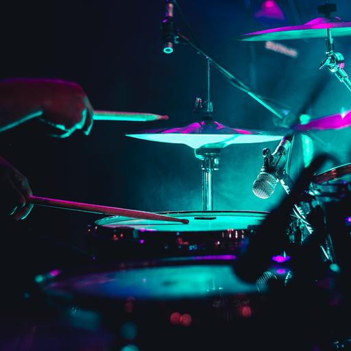 Nahaufnahme eines Drumsets in neonfarbener Bühnenbeleuchtung.