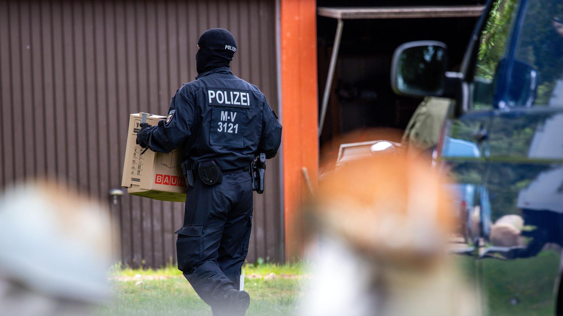 Ein Polizist trägt Beweismaterial über ein Grundstück, das im Zusammenhang mit der neonazi Gruppierung Hammerskins steht.