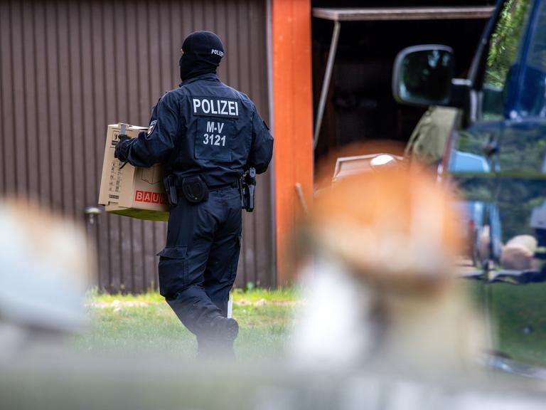 Ein Polizist trägt Beweismaterial über ein Grundstück, das im Zusammenhang mit der neonazi Gruppierung Hammerskins steht.