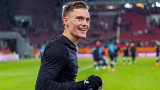 Der Fußballer Florian Wirtz auf dem Rasen. Er lacht.