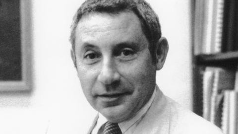 Der Astrophysiker Morton Roberts auf einer Schwarz-Weiß-Aufnahme. Er trägt einen hellen Anzug, ein helles Hemd und Schlips und lächelt verhalten. 