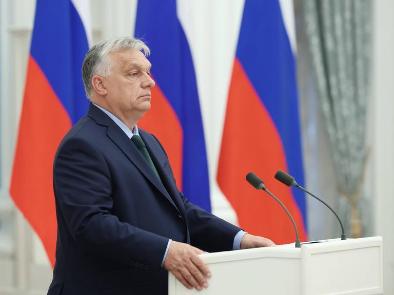 Viktor Orbán steht vor russischen Flaggen am Rednerpult und ist im Profil zu sehen