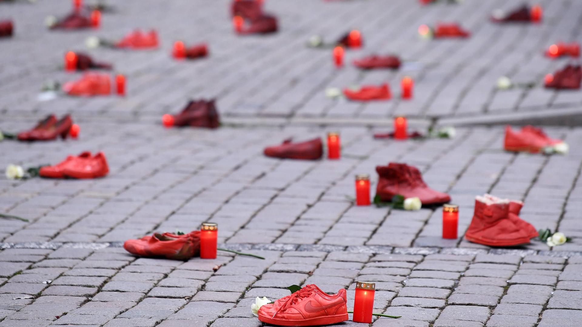 Schuh-Aktion zum Thema Femizide zum Internationalen Tag gegen Gewalt an Frauen am 25.11.2021 in Tübingen: Rote Schuhpaare stehen zusammen mit Grablichtern und weißen Rosen auf dem Tübinger Marktplatz.