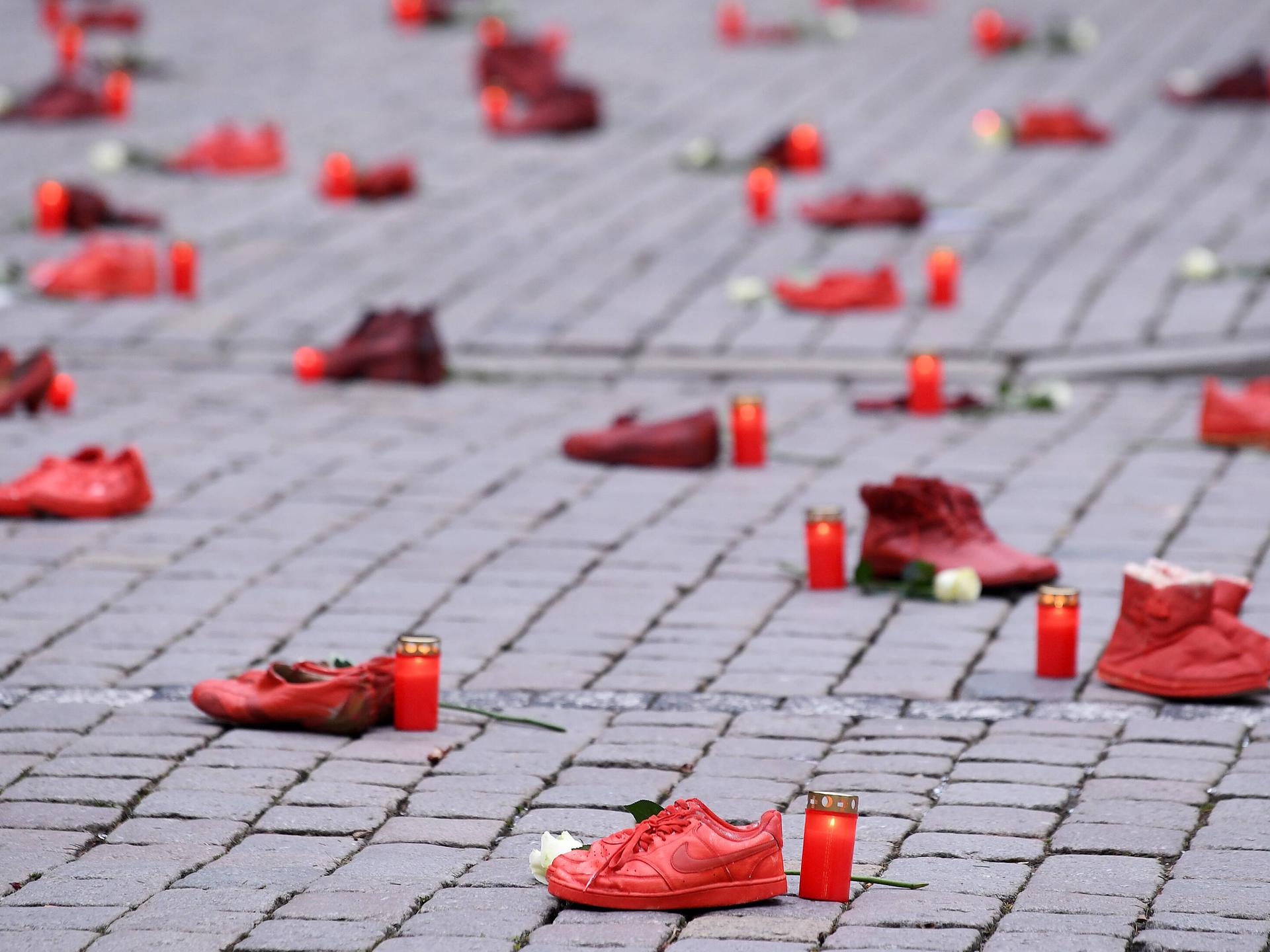 Schuh-Aktion zum Thema Femizide zum Internationalen Tag gegen Gewalt an Frauen am 25.11.2021 in Tübingen: Rote Schuhpaare stehen zusammen mit Grablichtern und weißen Rosen auf dem Tübinger Marktplatz.