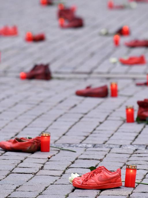 Schuh-Aktion zum Thema Femizide zum Internationalen Tag gegen Gewalt an Frauen am 25.11.2021 in Tübingen: Rote Schuhpaare stehen zusammen mit Grablichtern und weißen Rosen auf dem Tübinger Marktplatz.