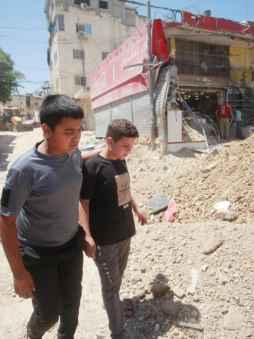 Zwei Kinder laufen an Trümmern im Gazastreifen vorbei. 