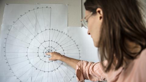 Catherine Lamb weist mit dem Zeigefinger auf eine spiralförmige Grafik.