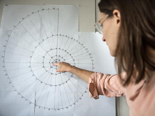 Catherine Lamb weist mit dem Zeigefinger auf eine spiralförmige Grafik.