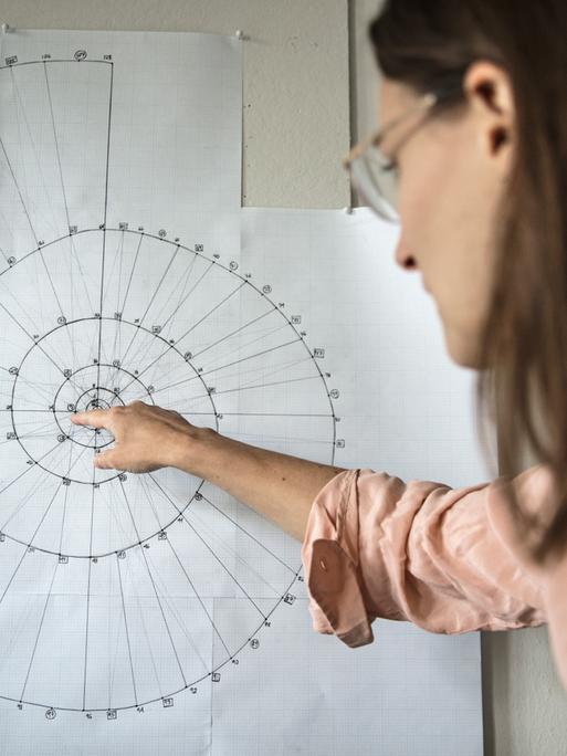 Catherine Lamb weist mit dem Zeigefinger auf eine spiralförmige Grafik.