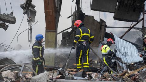 Ukraine, Kiew: Feuerwehrleute löschen ein Feuer nach einem Raketenangriff. Die ukrainische Hauptstadt geriet unter heftigen Beschuss durch russische Marschflugkörper.