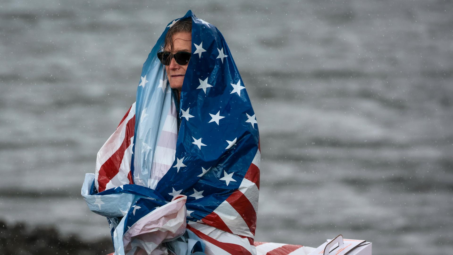Eine Frau hat sich eine amerikanischen Flagge über Kopf und Körper gewickelt.