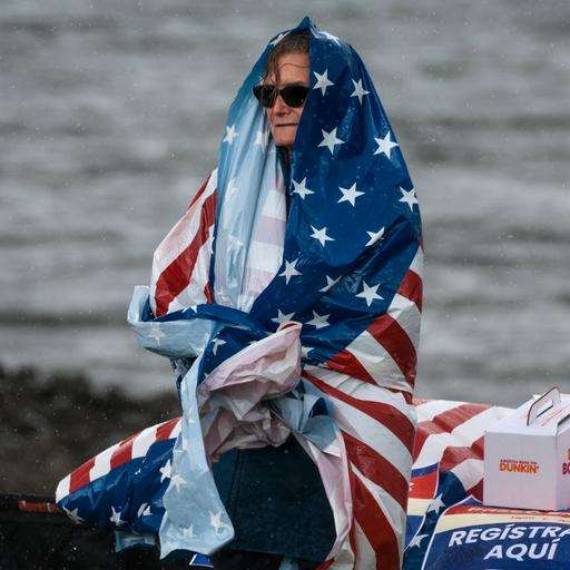 Eine Frau ist in eine Plastik-Tischdecke gewickelt, die mit der amerikanischen Flagge bedruckt ist.