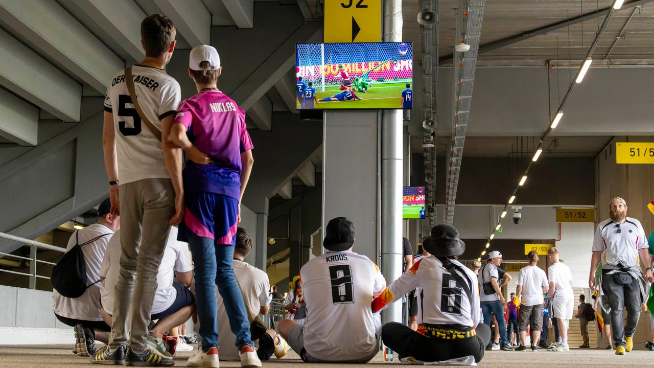 Deutschland-Fans schauen an einem Fernseher im Stadion das andere Spiel des Tages an