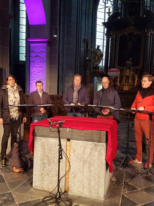 Man sieht das Ensemble Singer Pur beim Soundcheck vor einem Altar stehend. 