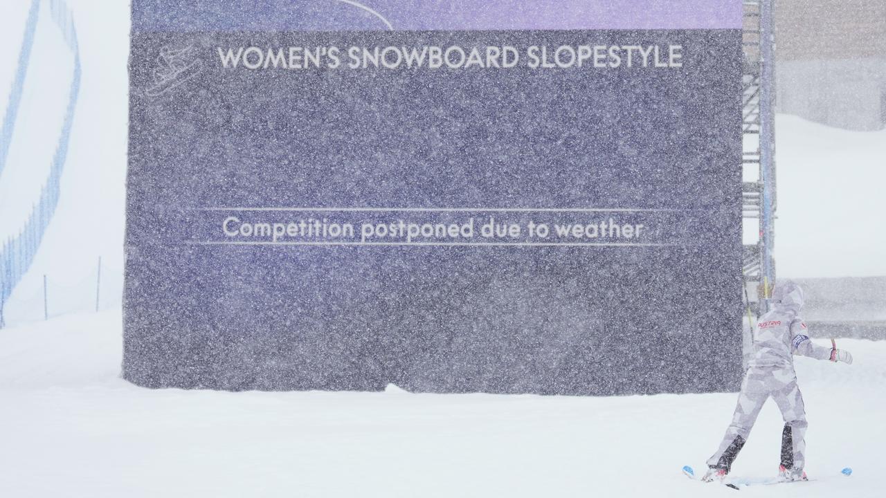 Inmitten dichten Schneefalls steht ein Schild mit der Aufschrift "Women's Snowboard Slopestyle - competiton postponed due to weather". 