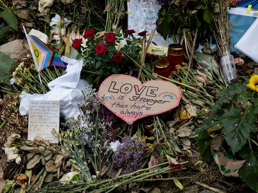 Nahaufnahme niedergelegter Blumen, Karten und LGBTIQ-Flaggen am Anschlagsort im Tiergarten.
