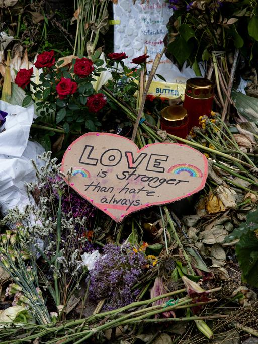 Nahaufnahme niedergelegter Blumen, Karten und LGBTIQ-Flaggen am Anschlagsort im Tiergarten.
