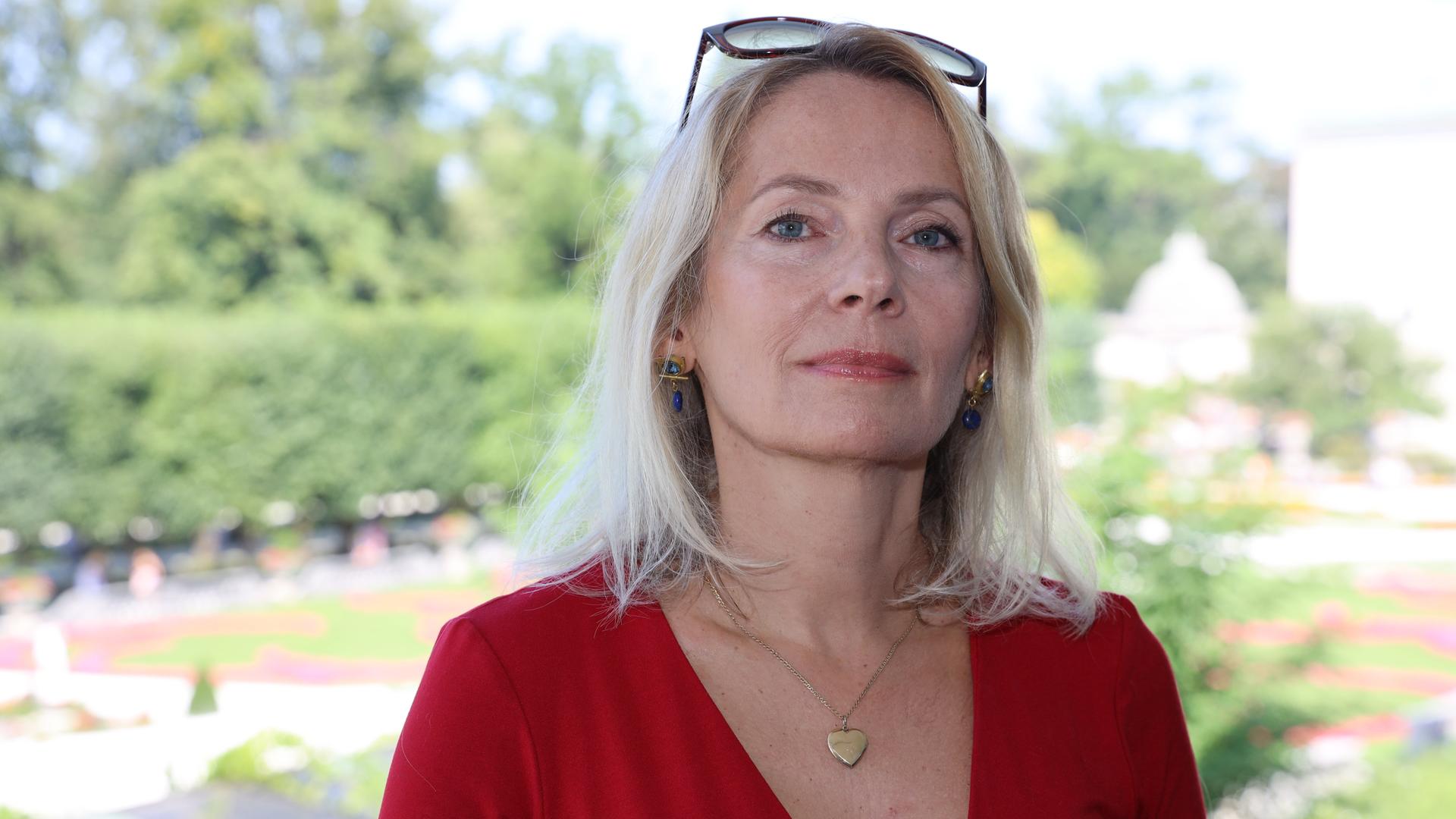 Joanna Bator steht im roten Kleid im Freien in einem Park Joanna Bator steht im roten Kleid im Freien in einem Park