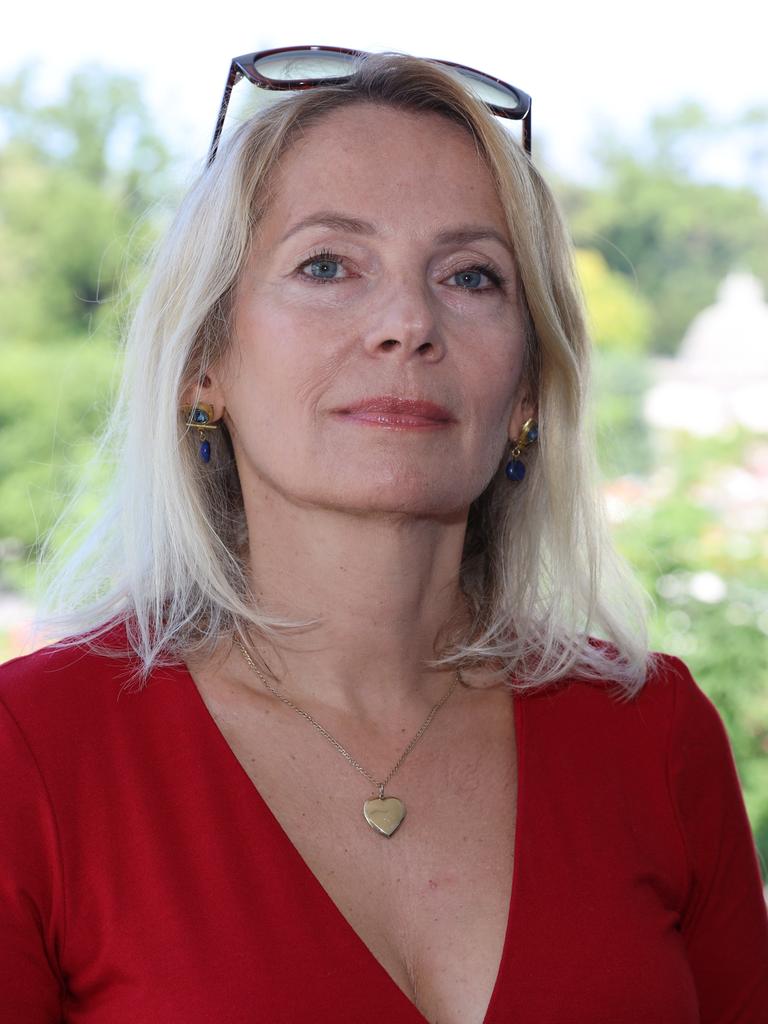 Joanna Bator steht im roten Kleid im Freien in einem Park