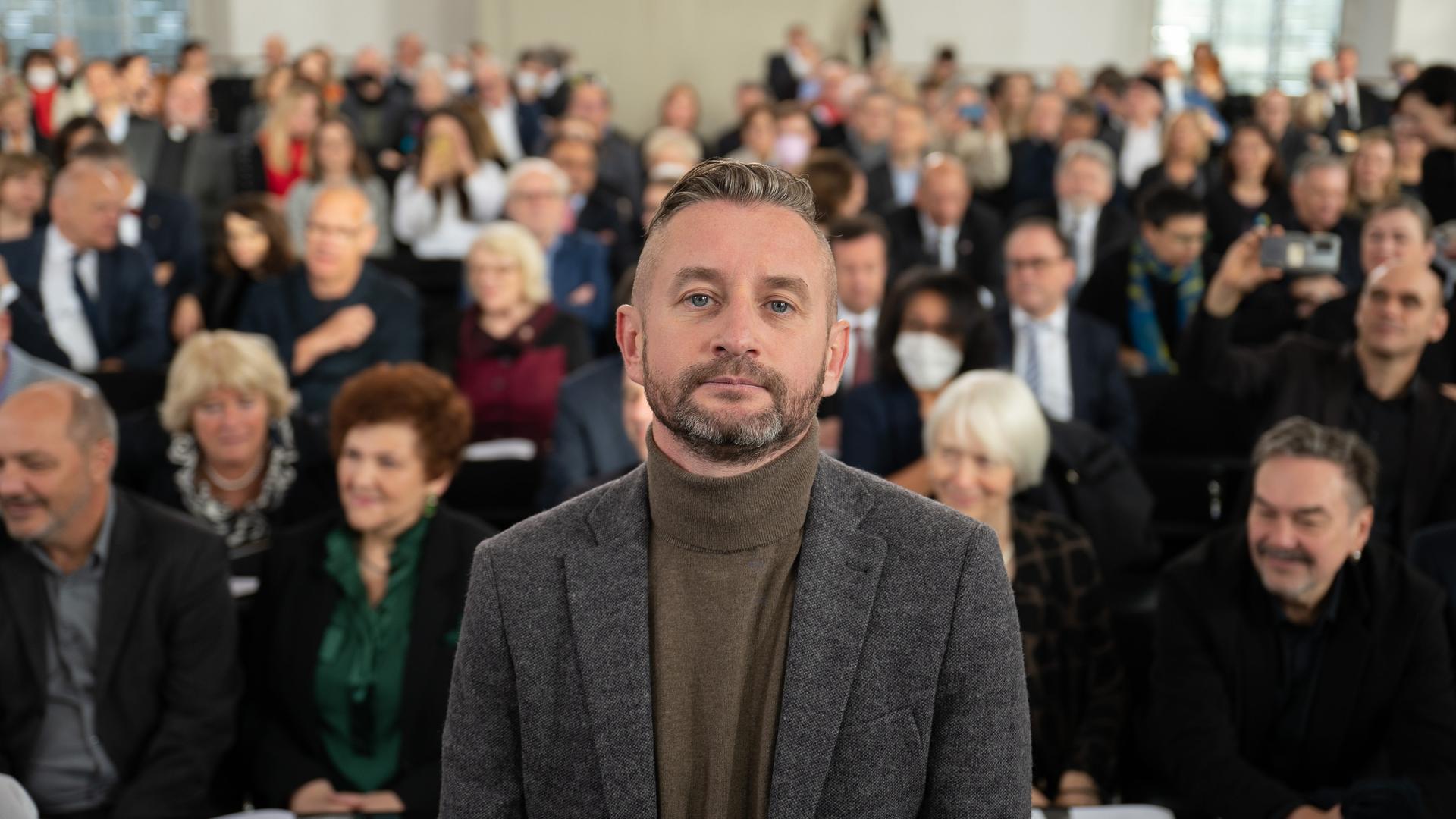 Ein Mann steht vor einem Publikum.