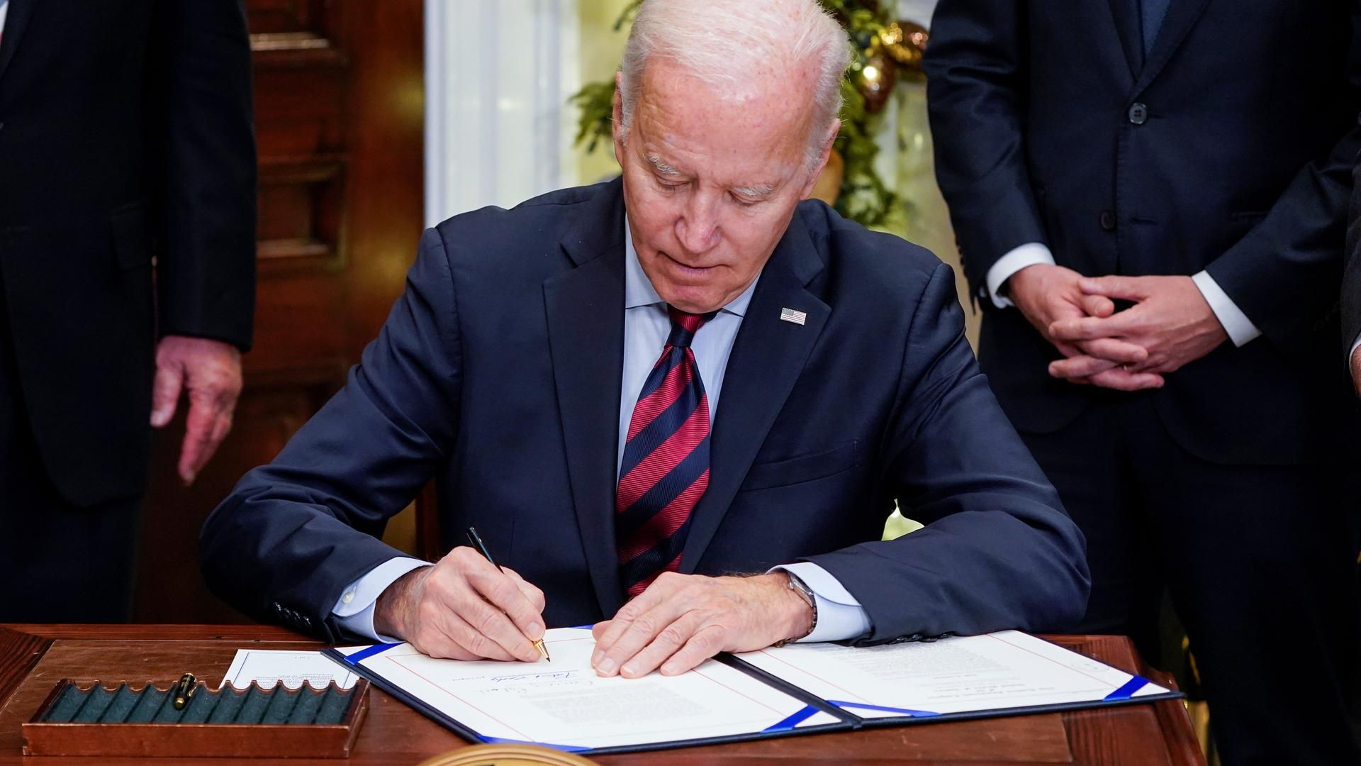 US-Präsident Joe Biden unterzeichnet ein Papier an seinem Schreibtisch im Weißen Haus.
