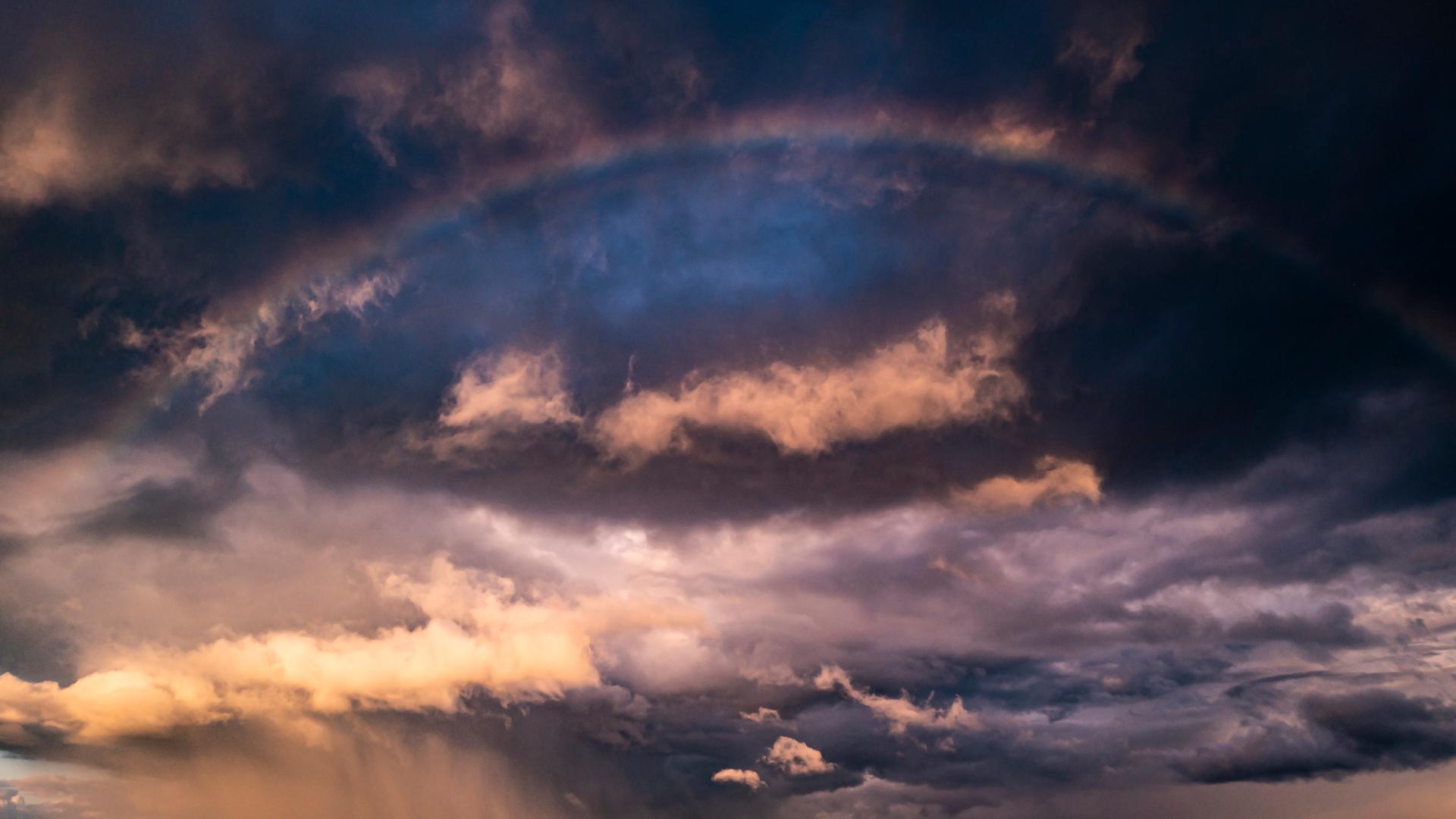 Dramatischer Himmel: Sturmwolken und ein Regenbogen.