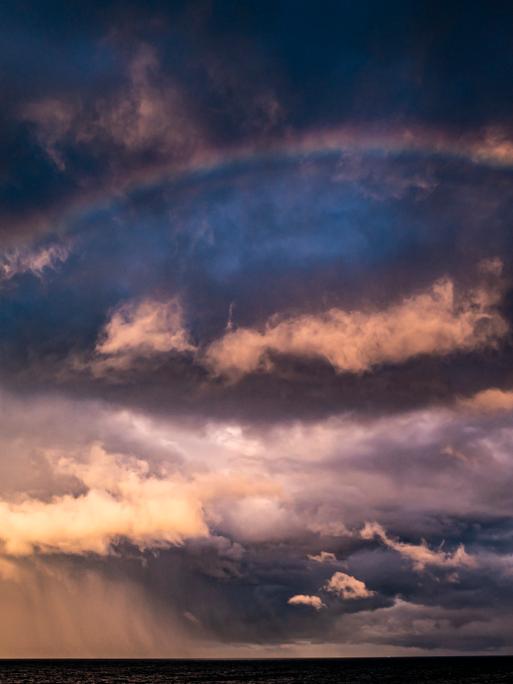 Dramatischer Himmel: Sturmwolken und ein Regenbogen.