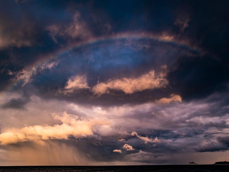 Dramatischer Himmel: Sturmwolken und ein Regenbogen.