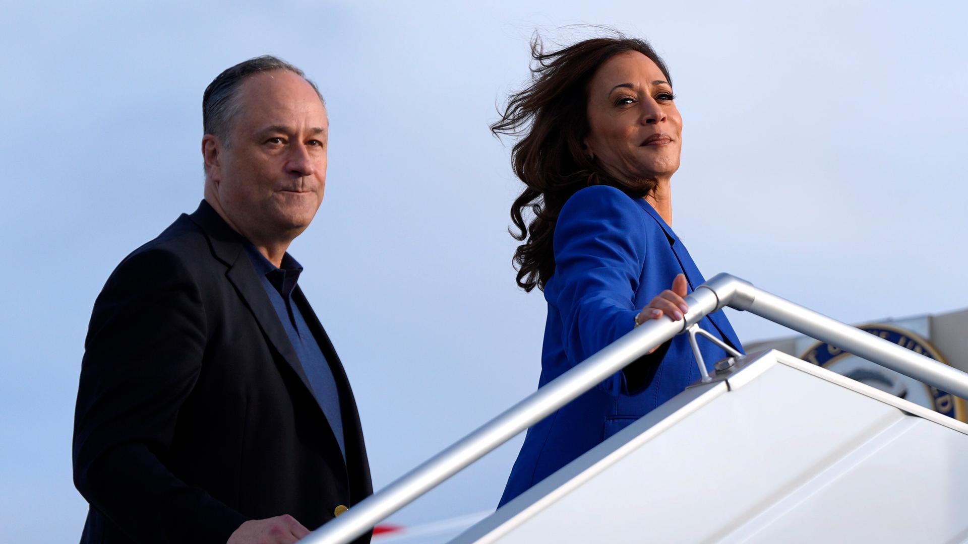 Doug Emhoff und Kamala Harris gehen an Board der Air Force Two und schauen von der Flugzeugtreppe.