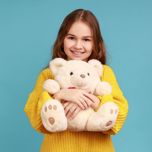Ein Mädchen mit langen Haaren und im gelben Pullover umarmt einen Teddybär