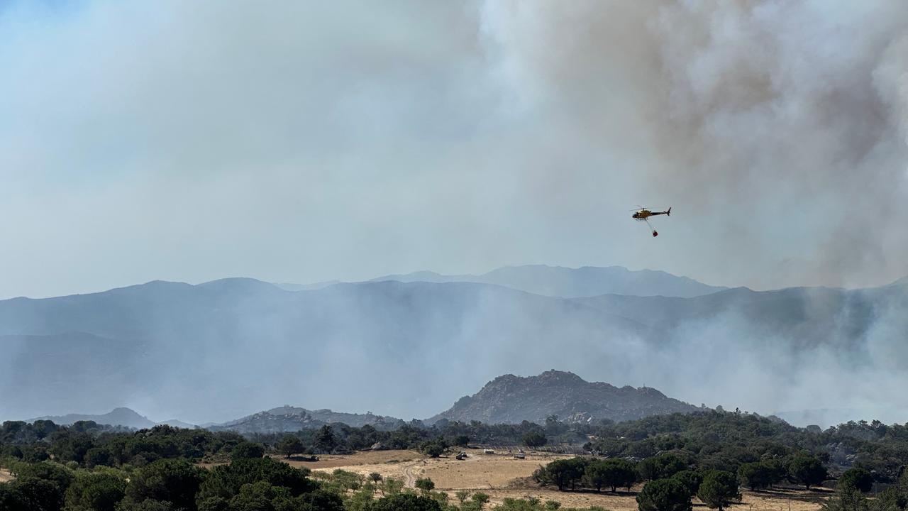 Feuerwehrleute bekämpfen einen Großbrand in der Nähe von Montalba-le-Château - ein Löschhubschrauber überfliegt das Gebiet. 
