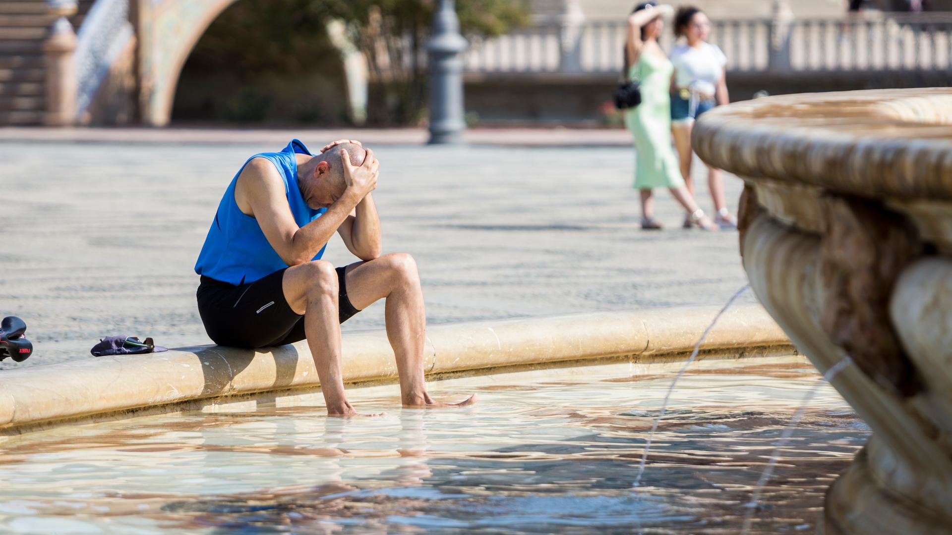 Ein Mann kühlt sich im zentralen Brunnen in Sevilla ab.