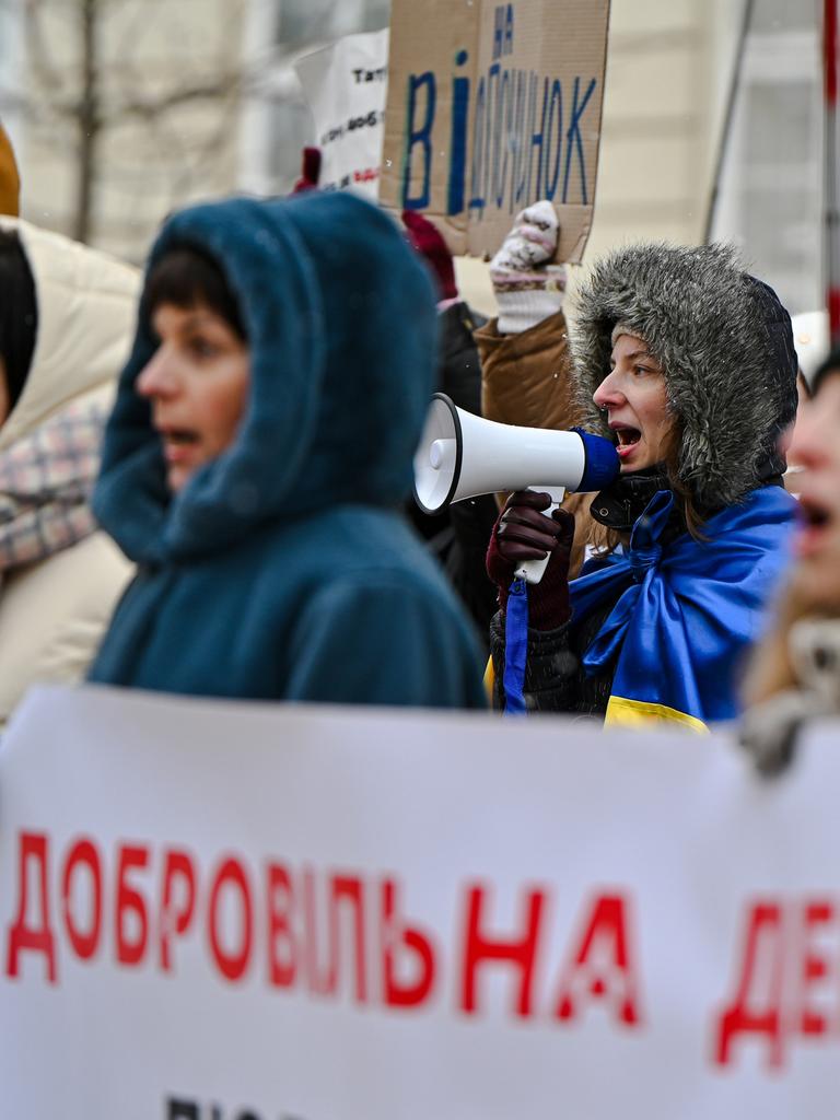 Eine Frau mit Megaphone steht in einer Gruppe von Frauen. Sie spricht in das Megaphone. Um ihr Schultern hat sie eine Ukrainefahne geknotet.