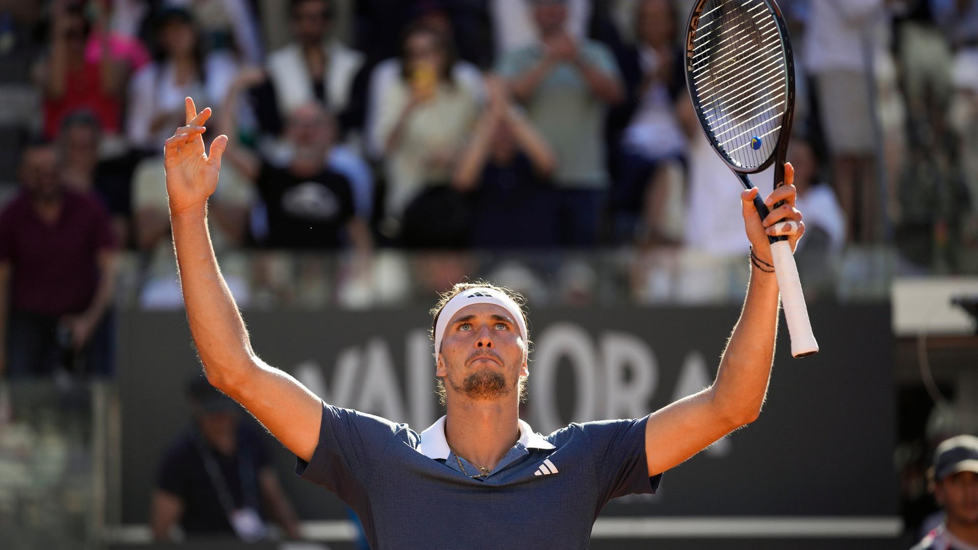 Das Foto zeigt den Tennisspieler Alexander Zverev. Er hält seinen Tennisschläger in der Hand und reckt beide Arme in die Höhe.