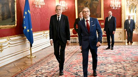 Bundespräsident Van der Bellen und der FPÖ-Vorsitzende Kickl gehen nebeneinander in der Wiener Hofburg einen Flur entlang.