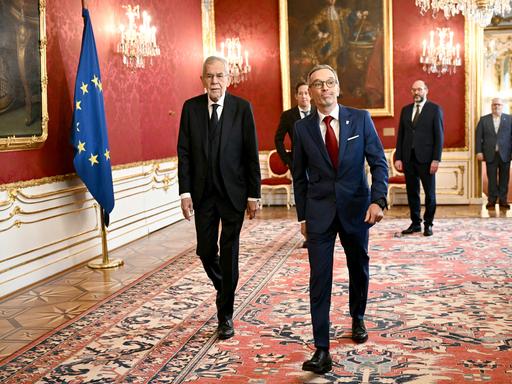 Bundespräsident Van der Bellen und der FPÖ-Vorsitzende Kickl gehen nebeneinander in der Wiener Hofburg einen Flur entlang.