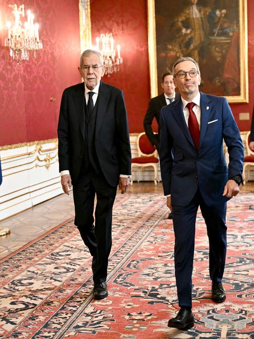 Bundespräsident Van der Bellen und der FPÖ-Vorsitzende Kickl gehen nebeneinander in der Wiener Hofburg einen Flur entlang.