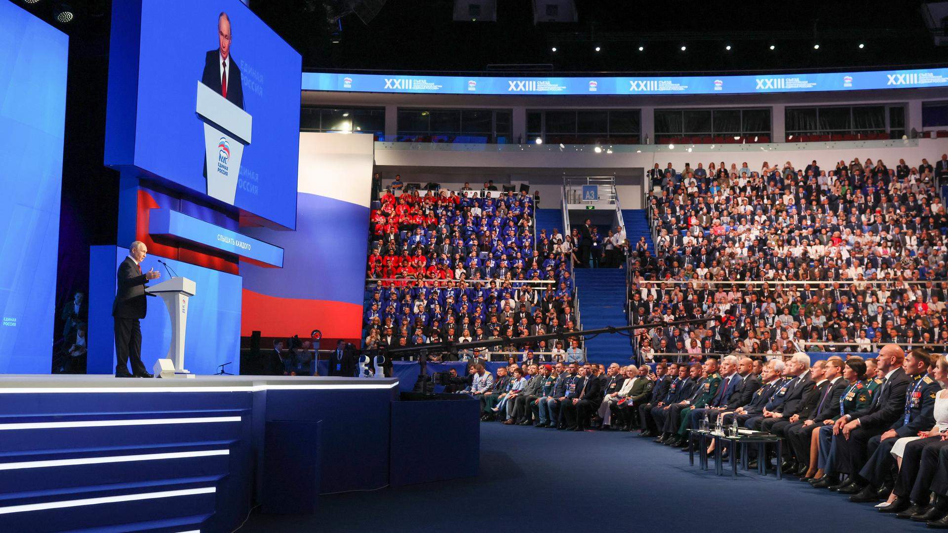DIESES FOTO WIRD VON DER RUSSISCHEN STAATSAGENTUR TASS ZUR VERFÜGUNG GESTELLT. Präsident und Parteichef Wladimir Putin steht im linken Bildrand am Rednerpult, im Hintergrund große Videoleinwände und die vollbesetzen Ränge des Moskauer Kongresszentrums. 