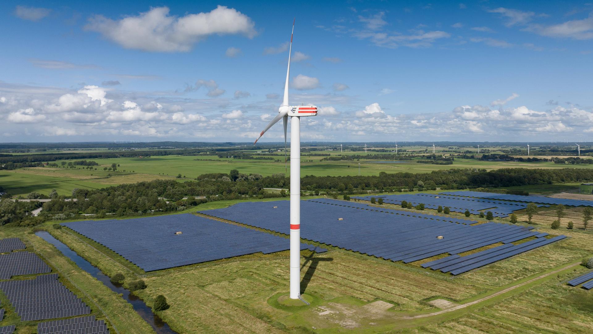 Solarenergie und Windenergie Eine Windkraftanlage dreht sich inmitten eines Solarparks in, Büttel Schleswig-Holstein Deutschland 