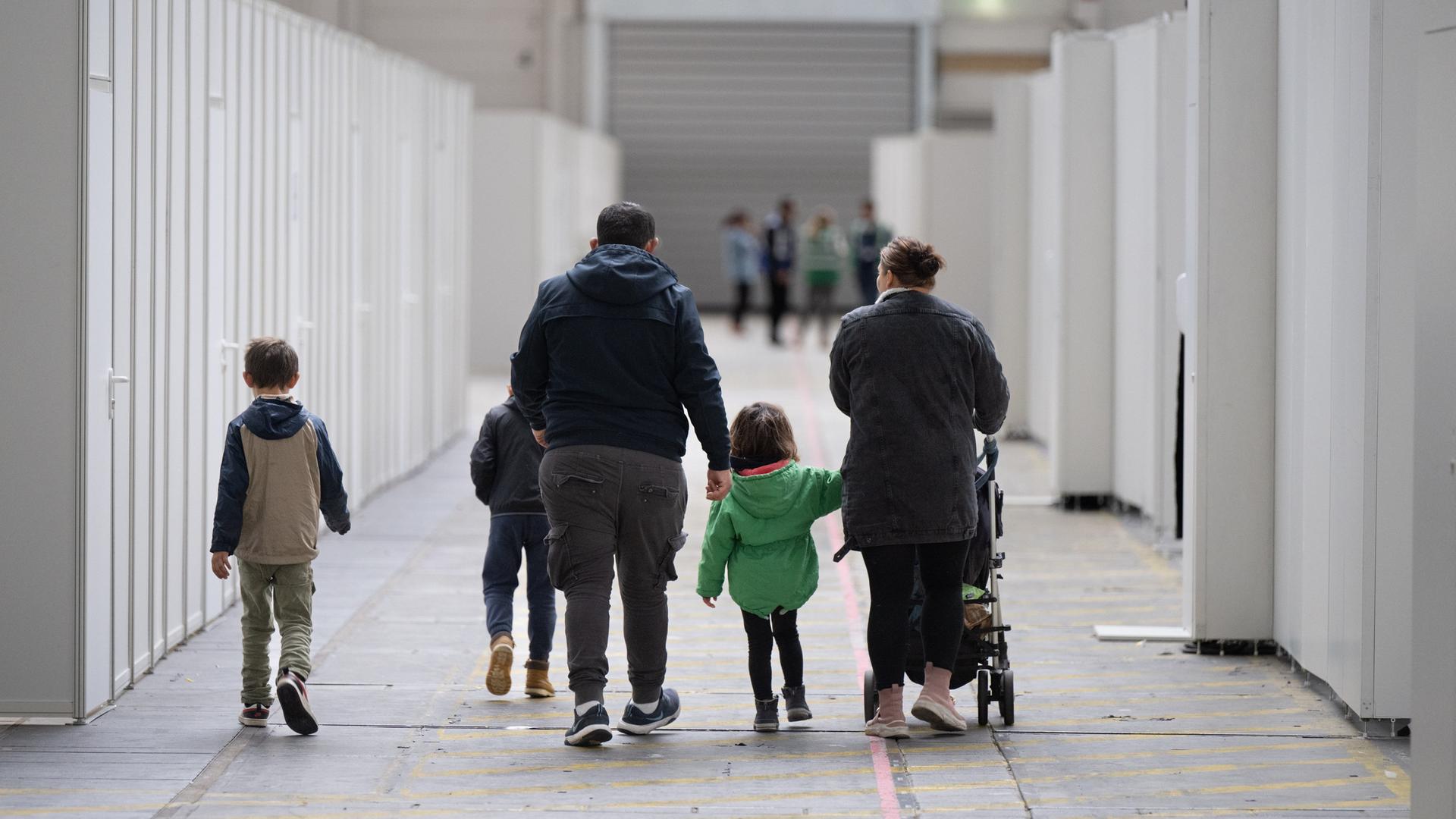 Eine Flüchtlingsfamilie geht durch die zu einer Massenunterkunft umfunktionierten Messehalle in Frankfurt.  