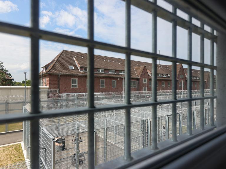 Blick aus einem Fenster der Abschiebehaftanstalt in Glückstadt auf das Nachbargebäude. Im Innenhof ein mit Stacheldraht umzäunter Außenbereich.