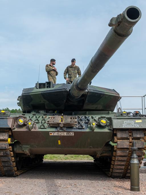 Ein Kampfpanzer auf dem zwei Soldaten stehen. Vor dem Fahrzeug steht Munition. Ein Kampfpanzer auf dem zwei Soldaten stehen. Vor dem Fahrzeug steht Munition.