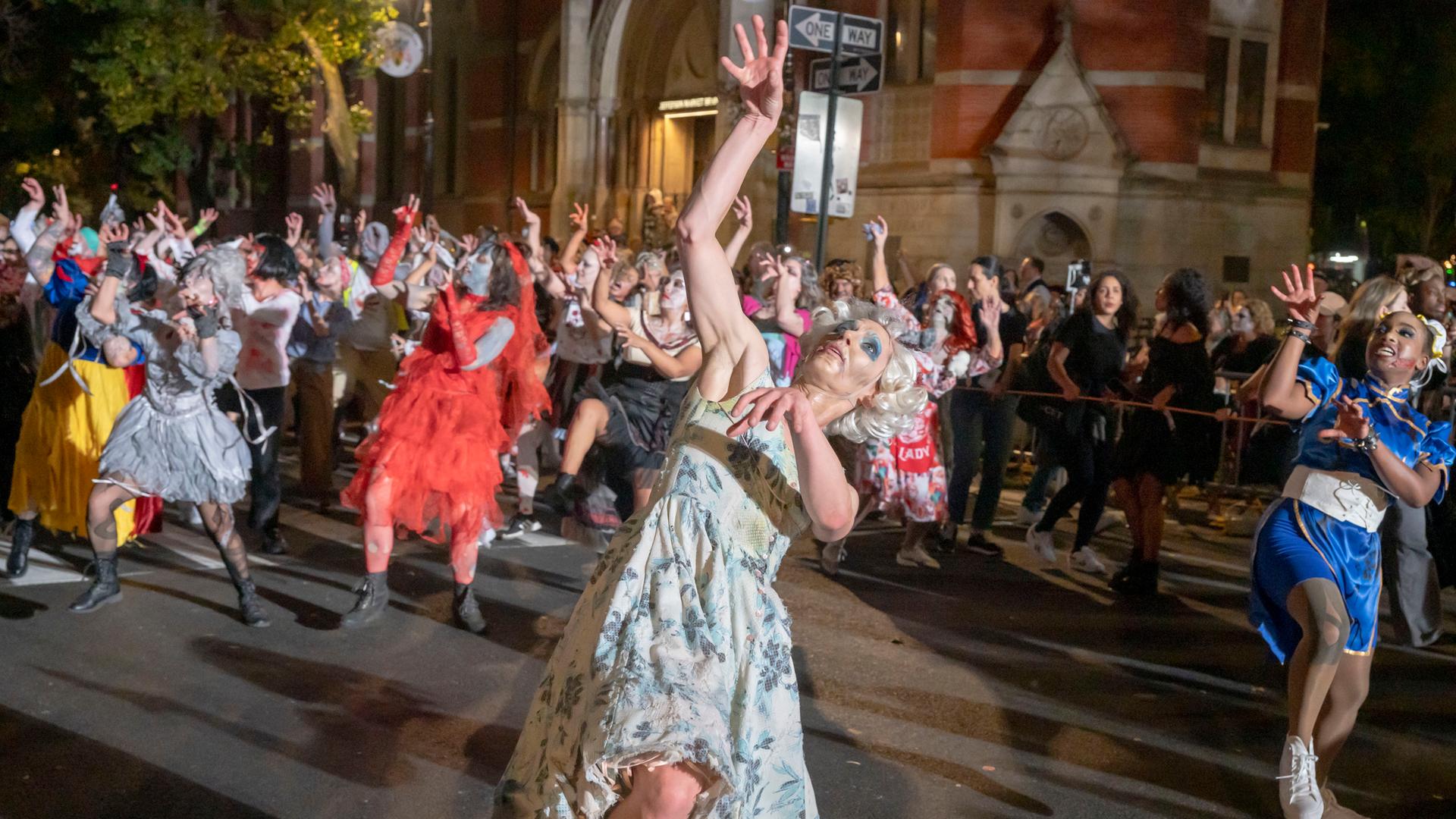 Menschen in verschiedenen Halloween-Kostümen tanzen mit merkwürdig verrenkten Gliedmaßen.