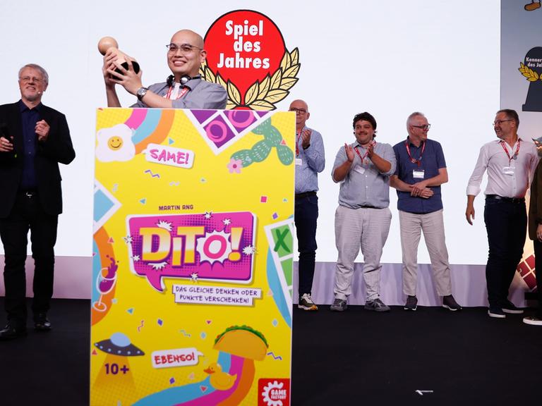 Martin Ang, Gewinner des "Spiel des Jahres 2026" mit dem Spiel "Dito!" jubelt neben Harald Schrapers, Vorsitzender des Vereins "Spiel des Jahres", während der Preisverleihung in Berlin.